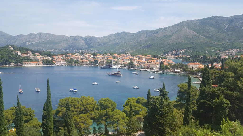 a view over cavtat harbour. a pretty harbour is lined by trees and pretty houses