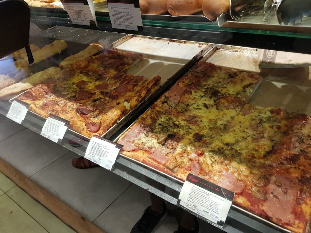 a bakery window displaying slices of pizza