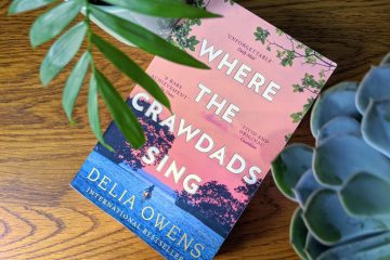 where the crawdads sing book on a wooden background with two pot plants